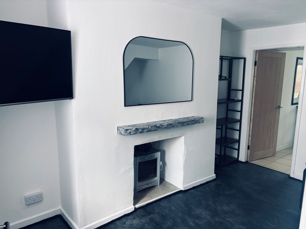 A living room with a television, mirror, and fireplace at Emily Rose Cottage in Bethesda