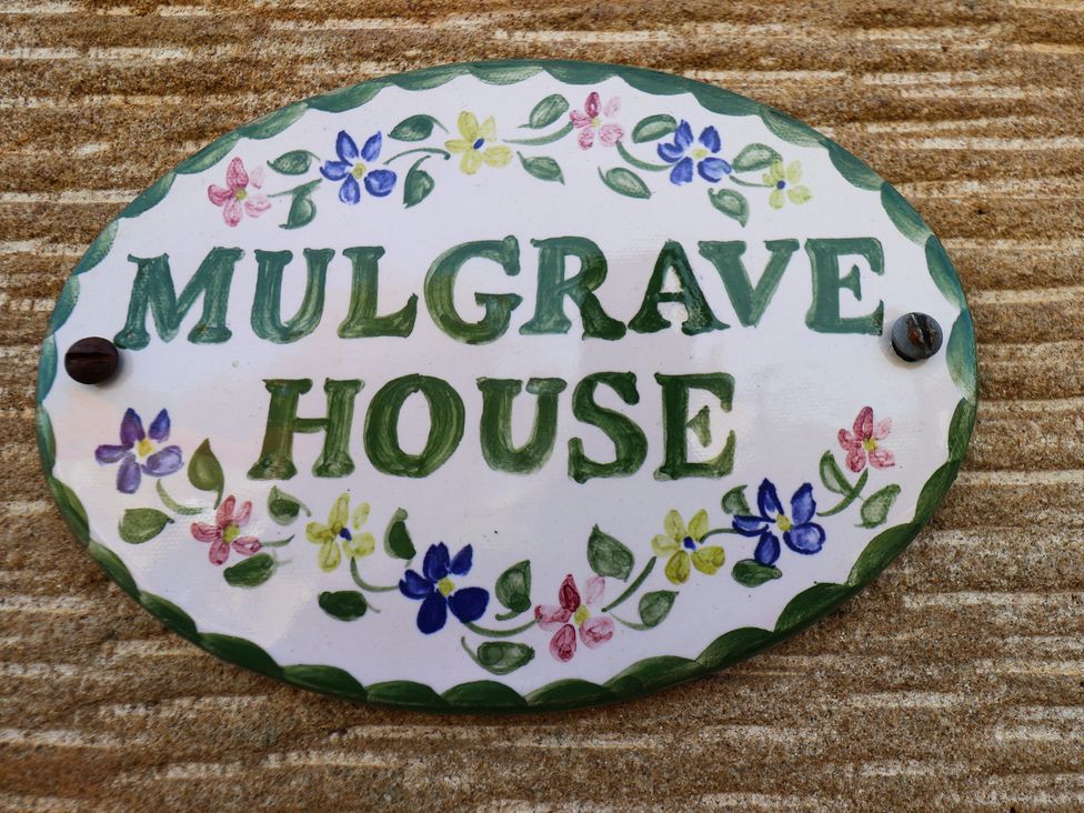 A nameplate with the text MULGRAVE HOUSE surrounded by decorative flowers at Mulgrave House in Hinderwell near Staithes