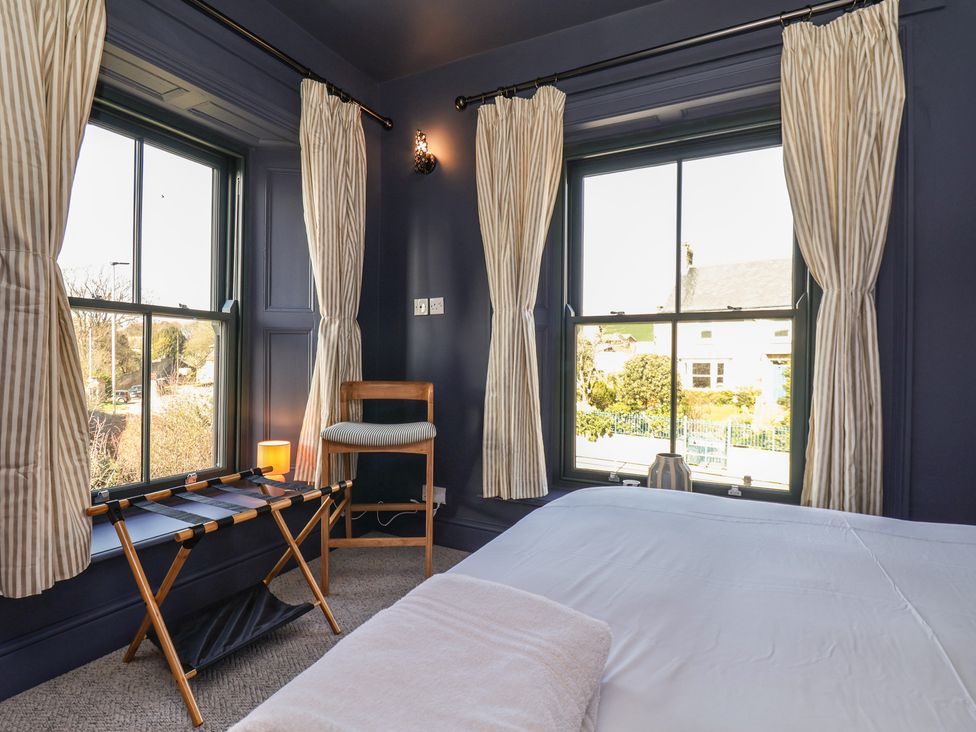 A bedroom with a bed and windows at Mulgrave House in Hinderwell near Staithes