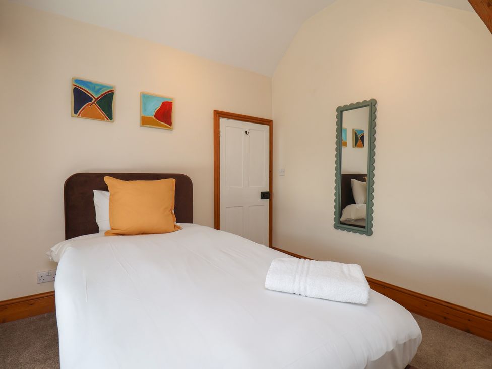 A bedroom with a bed, mirror, and paintings at Mulgrave House in Hinderwell near Staithes