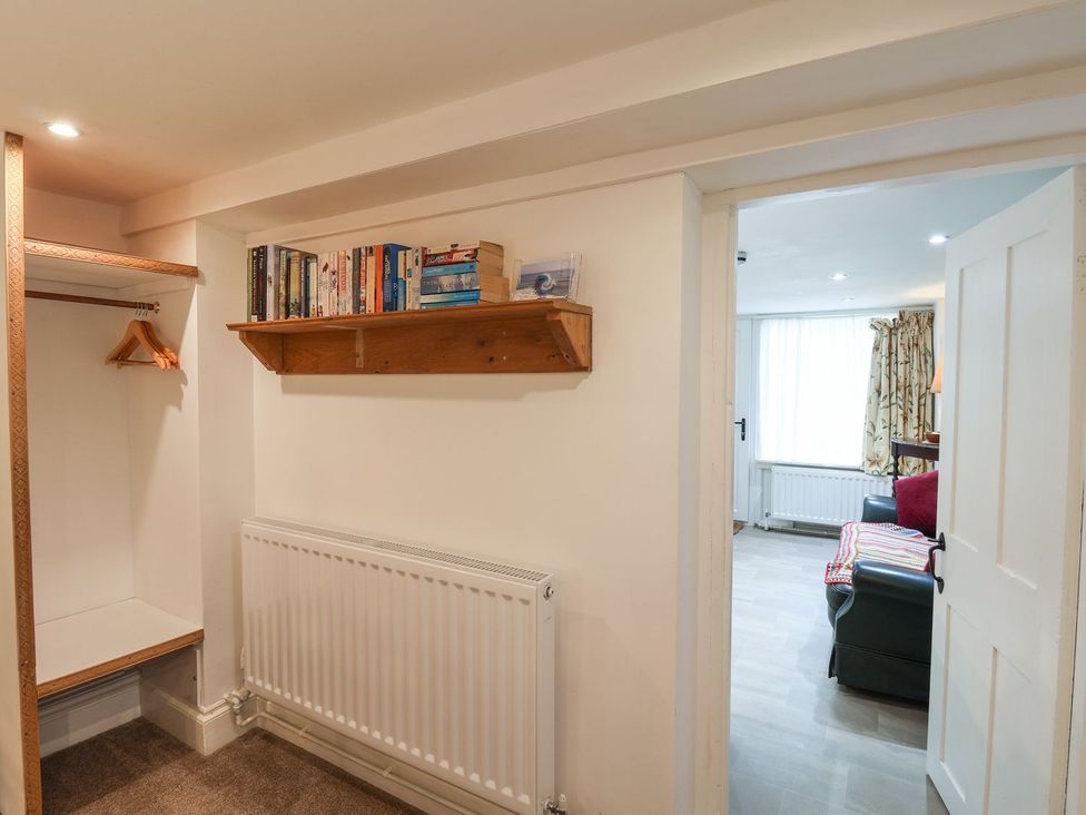 A hallway with a coat hanger and books on a shelf at Apartment at Mulgrave House Saltburn-by-the-Sea