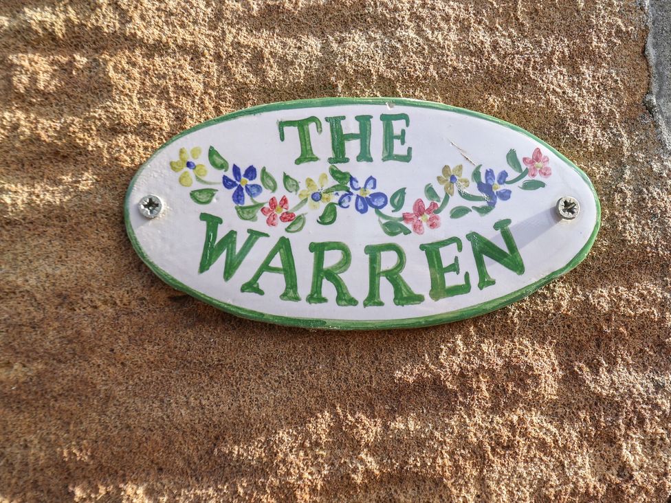 A nameplate that says The Warren attached to granite stone