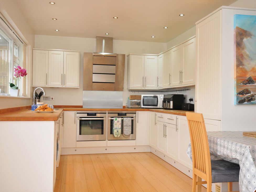 A kitchen with appliances and dining table at Porthmeor in Wadebridge
