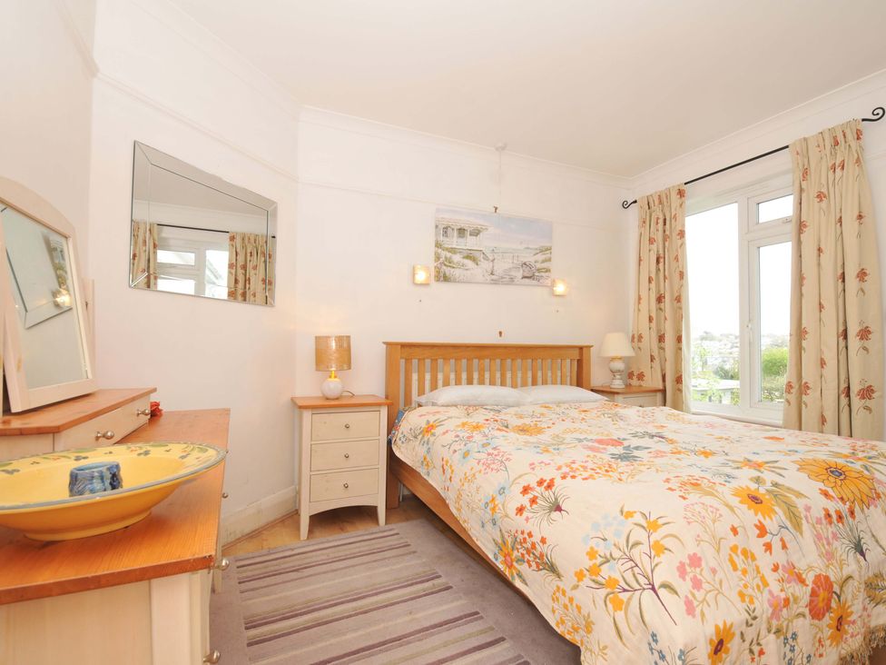 A bedroom with a bed and a dresser with a mirror at Porthmeor in Wadebridge