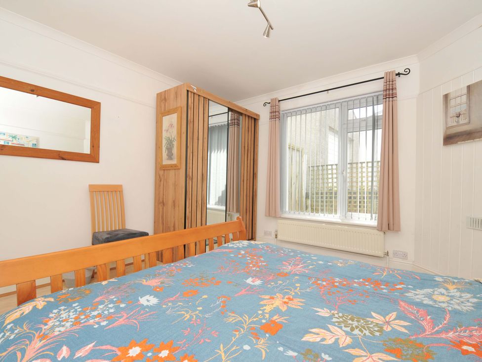 A bedroom with a bed and a mirror at Porthmeor in Wadebridge