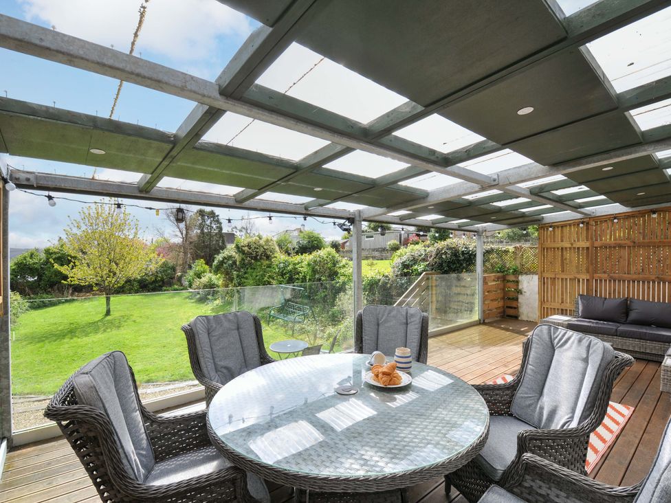 A conservatory with a glass table and chairs overlooking a garden at Porthmeor in Wadebridge