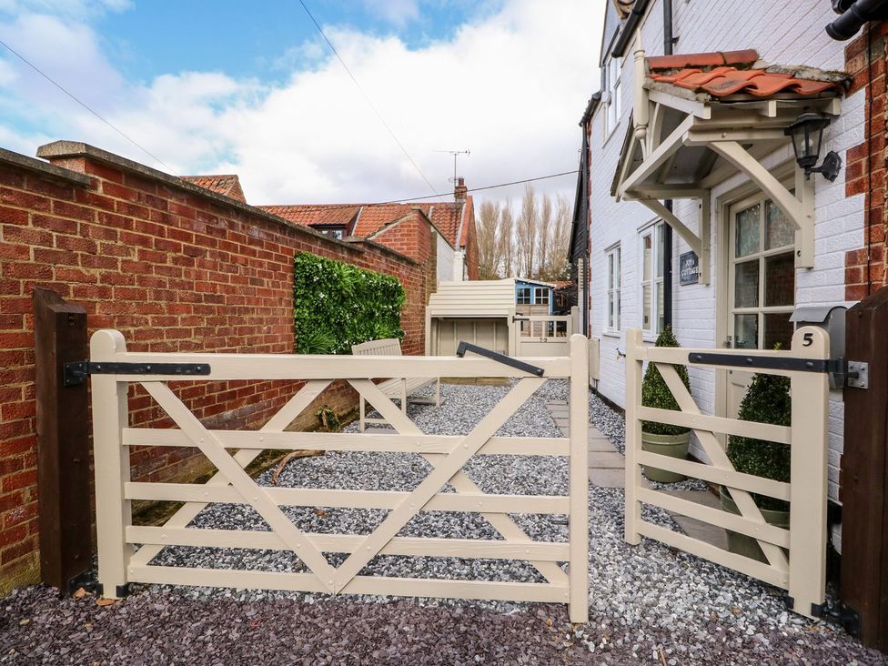An outdoor area with a gate and gravel pathway at Joy's Cottage in Snettisham