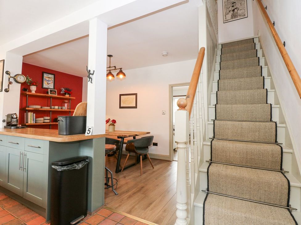 A kitchen with a staircase and dining area at Joy's Cottage Snettisham