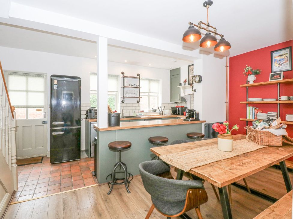 A kitchen with a table and stools at Joy's Cottage in Snettisham