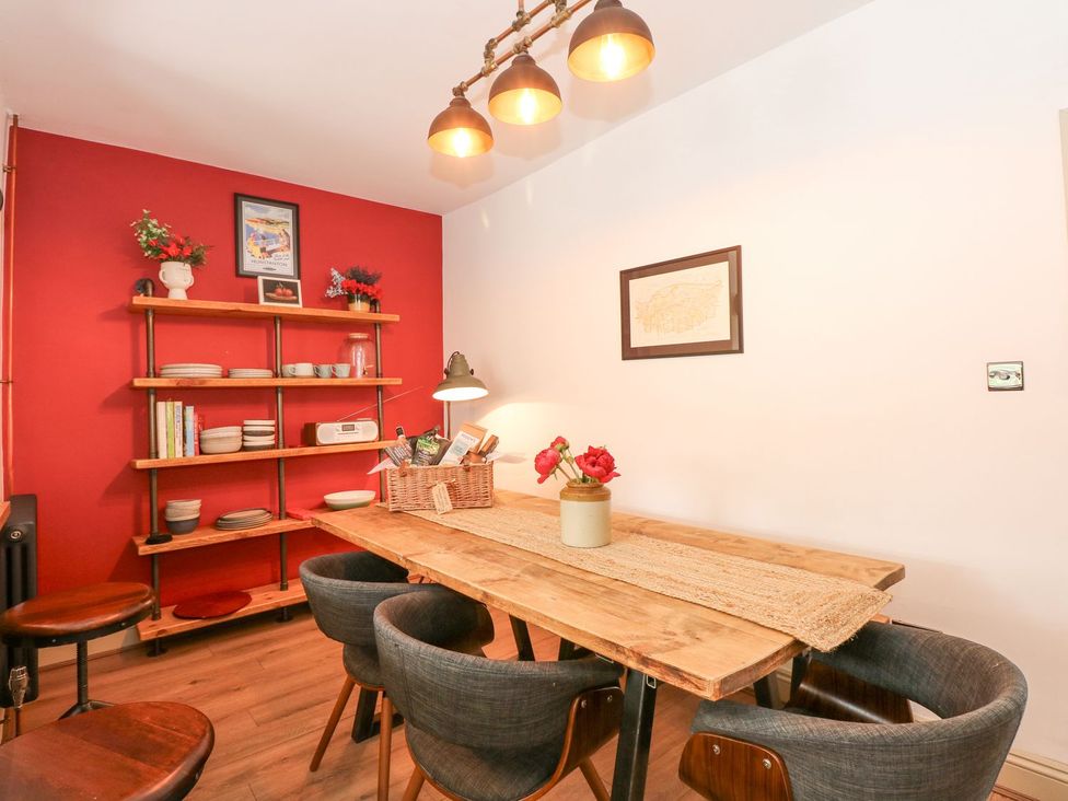 A dining room with a table, chairs, and shelving at Joy's Cottage in Snettisham