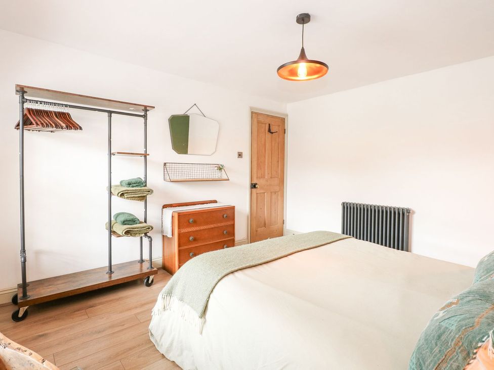 A bedroom with a bed and storage furniture at Joy's Cottage in Snettisham