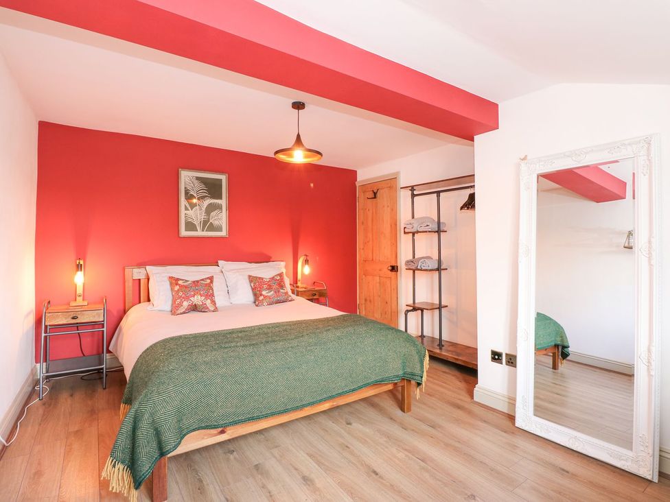 A bedroom with a double bed and mirror at Joy's Cottage in Snettisham