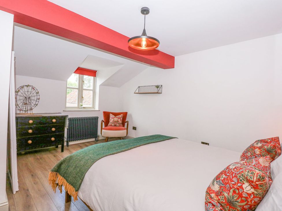 A bedroom with a bed and chair at Joy's Cottage in Snettisham