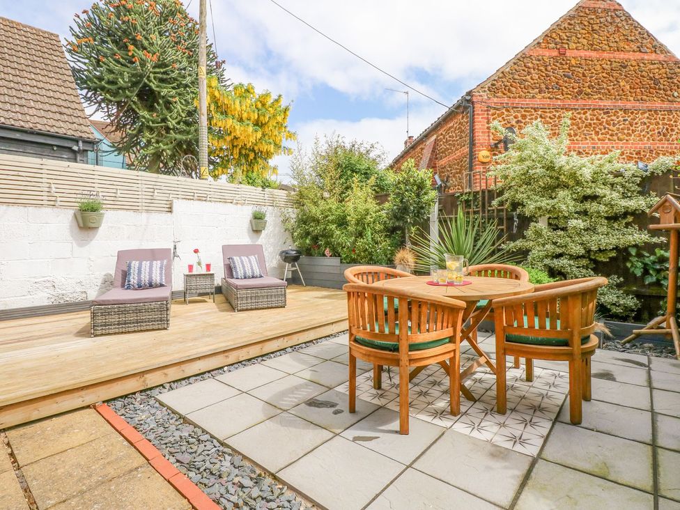 A garden with a table and chairs and lounge chairs at Joy's Cottage Snettisham
