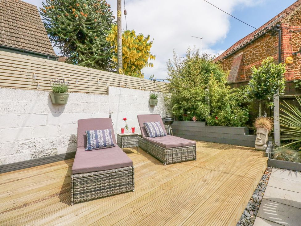 A garden with lounge chairs and potted plants at Joy's Cottage in Snettisham