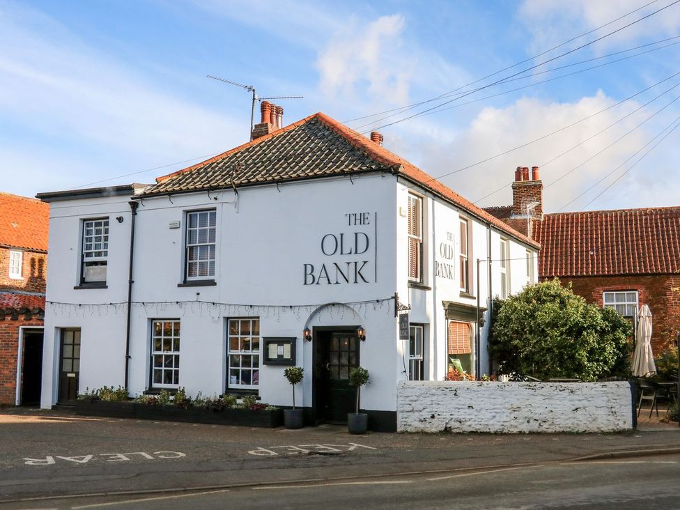 A pub building with signage and outdoor seating at The Old Bank in Snettisham