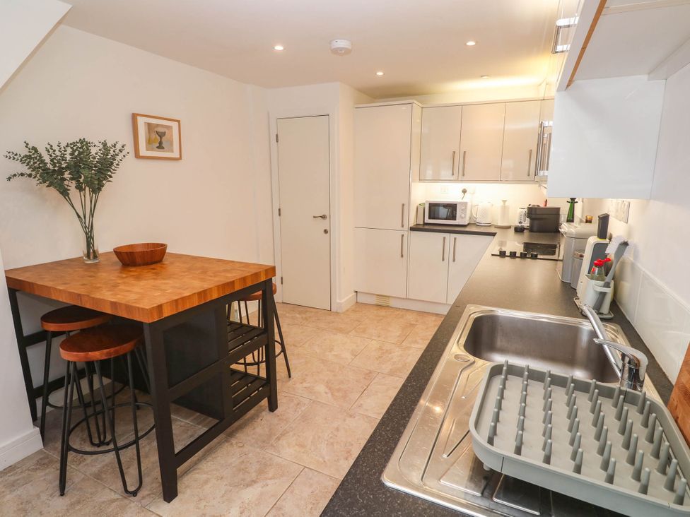 A kitchen with a table and stools at 11 Fountain Court in Falmouth
