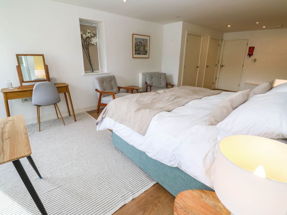 A bedroom with a bed, dresser, armchair, and lamp at 11 Fountain Court in Falmouth