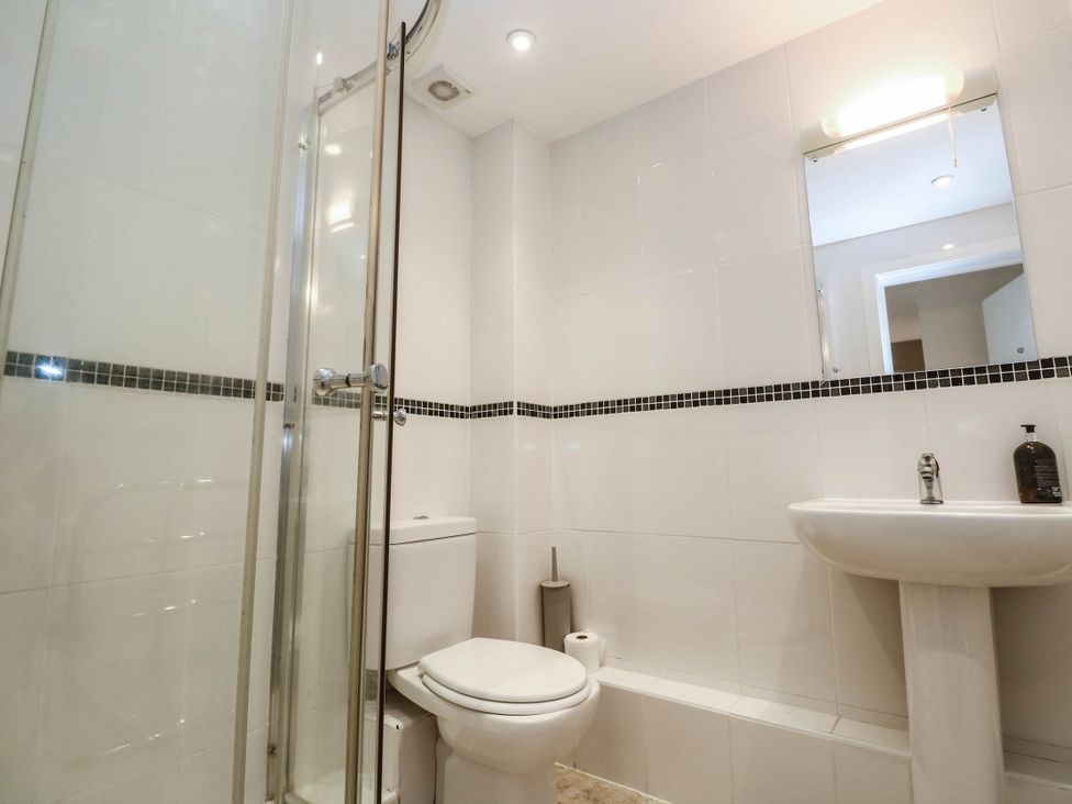 A bathroom with a shower, toilet, and washbasin at 11 Fountain Court in Falmouth