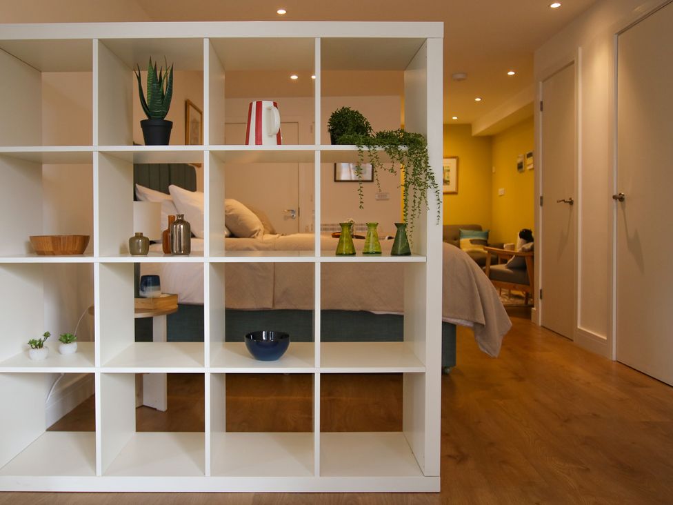 A bedroom with a shelf unit displaying various items at 11 Fountain Court in Falmouth