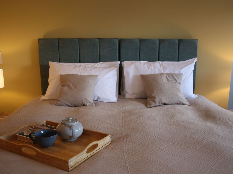 A bedroom with a bed and tray containing tea and books at 11 Fountain Court in Falmouth