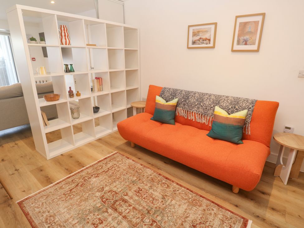 A living room with a sofa and bookshelf at 11 Fountain Court in Falmouth
