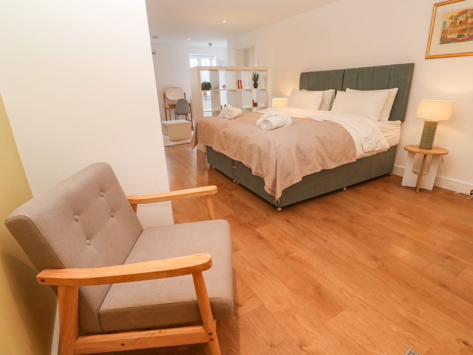 A bedroom with a bed and chair at 11 Fountain Court in Falmouth