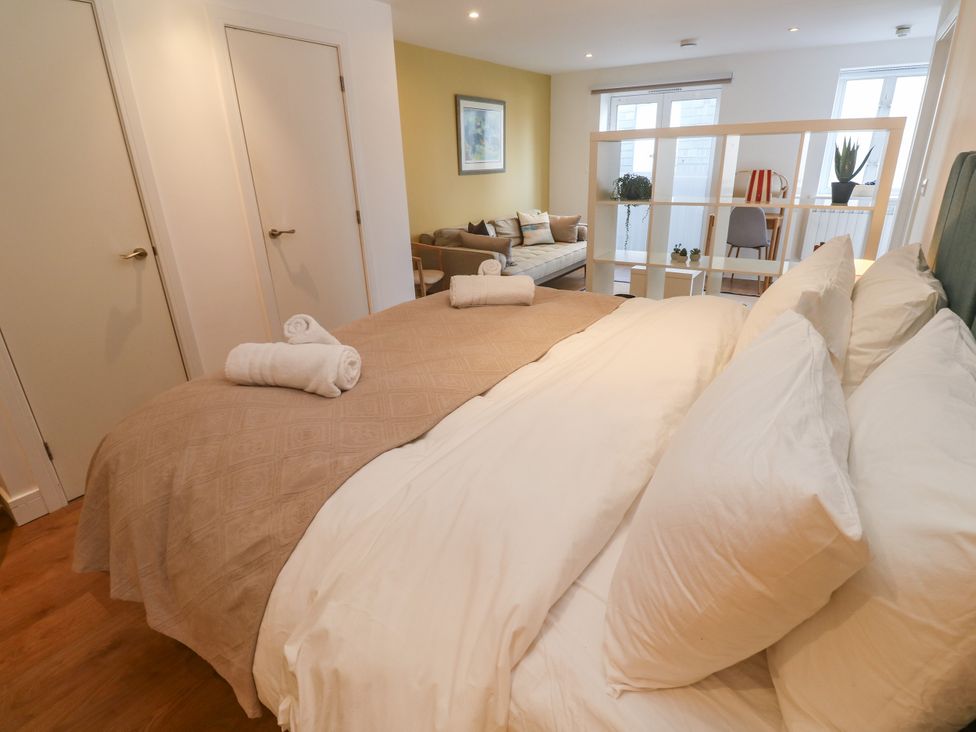A bedroom with a bed and sofa separating areas at 11 Fountain Court Falmouth