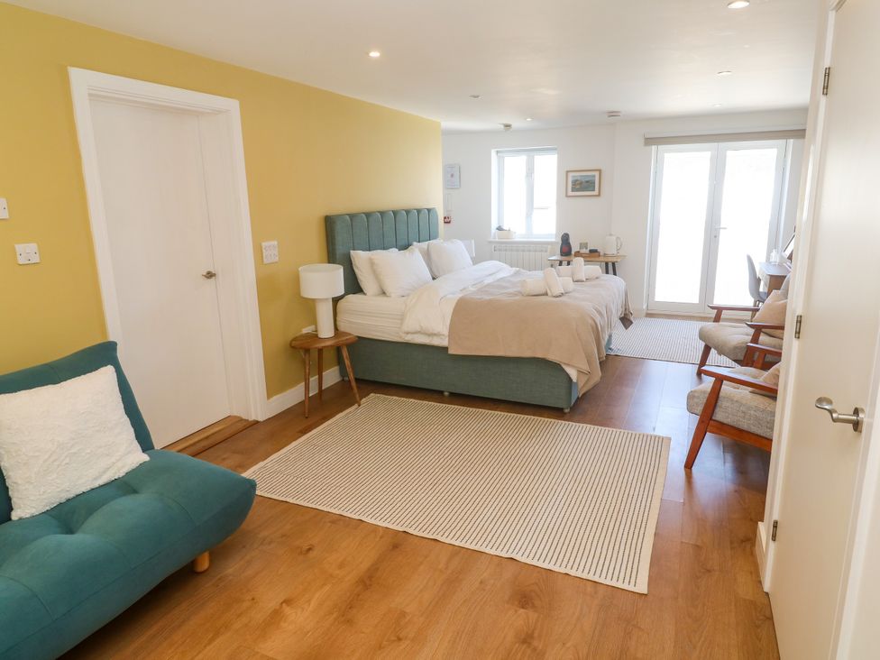 A bedroom with a bed, sofa and chairs at 11 Fountain Court in Falmouth