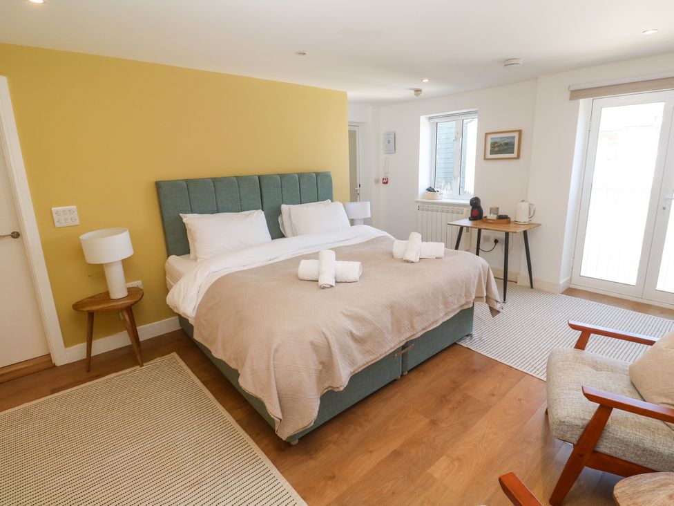 A bedroom with a bed and a chair at 11 Fountain Court in Falmouth