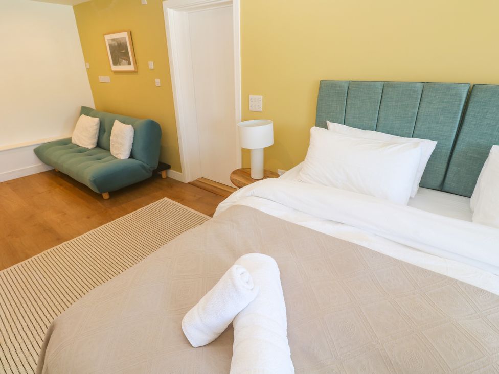 A bedroom with a bed and sofa at 11 Fountain Court in Falmouth