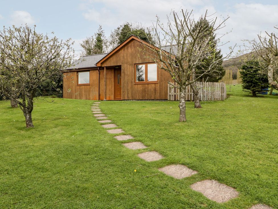 A cottage with a path and trees at Orchard Cottage in Ledbury