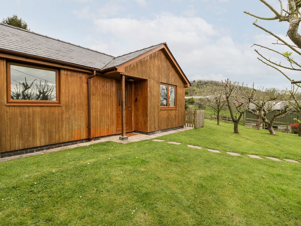 A wooden exterior with a front door and garden at Orchard Cottage in Ledbury