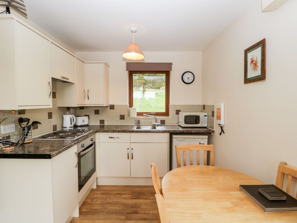 A kitchen with an oven, sink, and table at Orchard Cottage in Ledbury