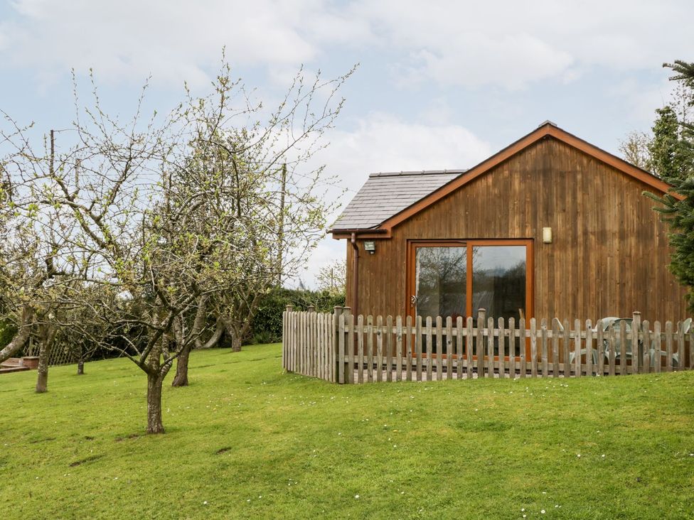A cabin with a wooden exterior in a garden at Orchard Cottage Ledbury