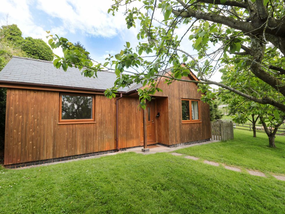 A wooden house with a front door and windows at Orchard Cottage in Ledbury