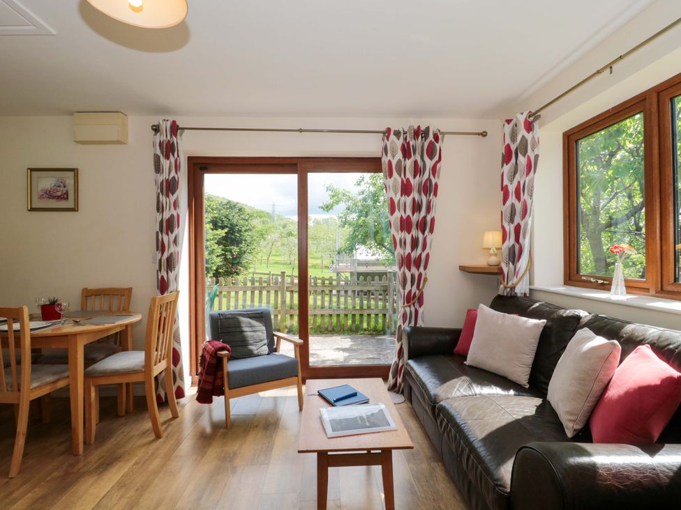 A living room with a sofa and dining table at Orchard Cottage in Ledbury