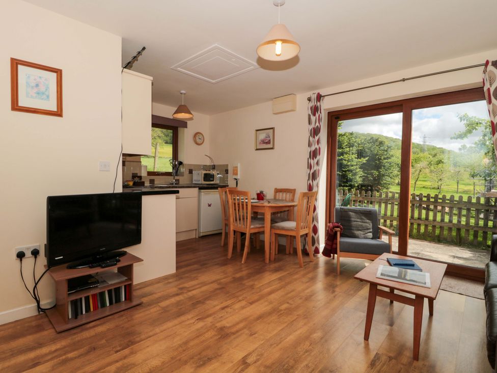 A living room with a television and dining area at Orchard Cottage in Ledbury