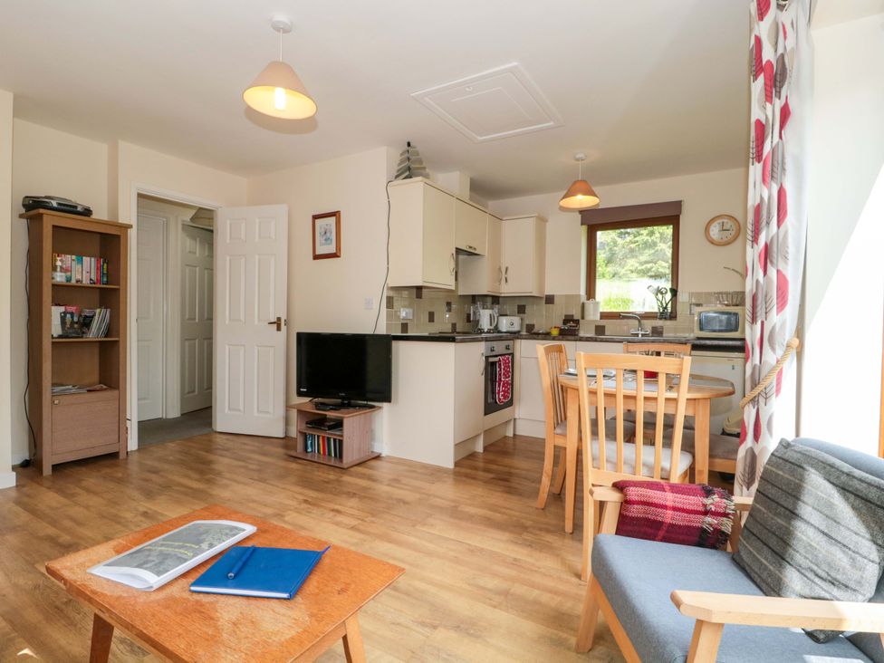 A living room with a kitchen area and a television at Orchard Cottage in Ledbury