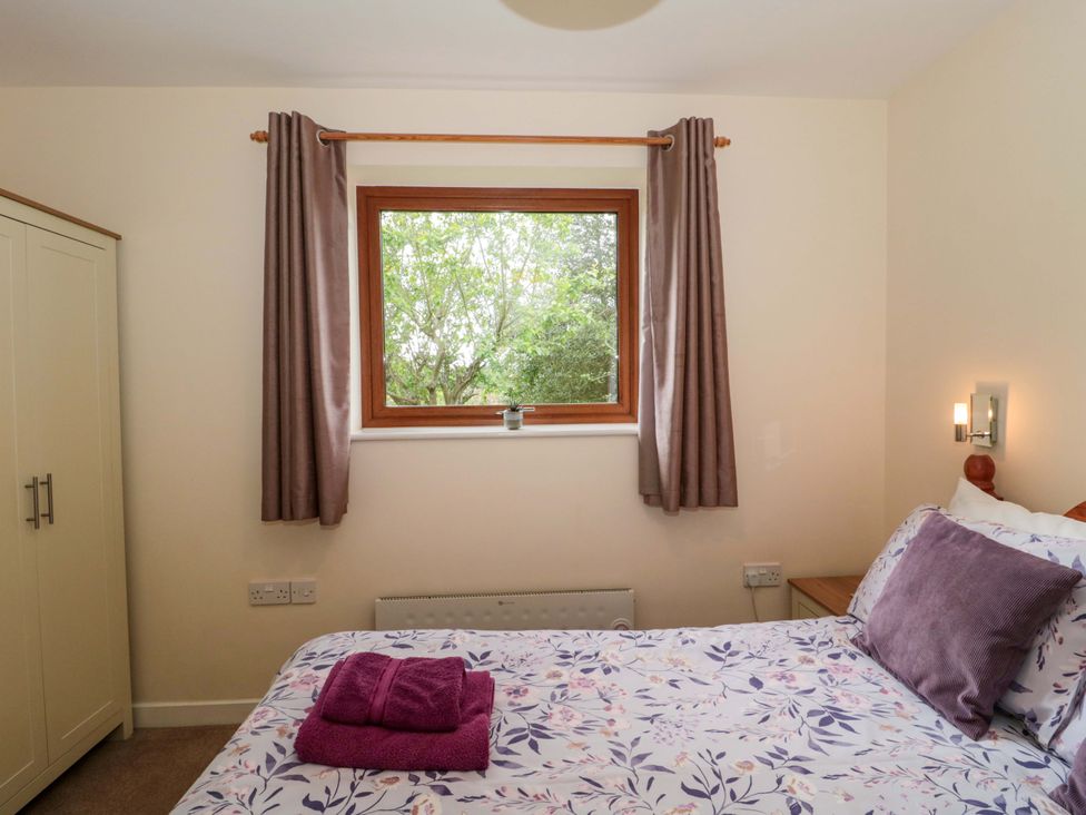 A bedroom with a bed and window at Orchard Cottage in Ledbury