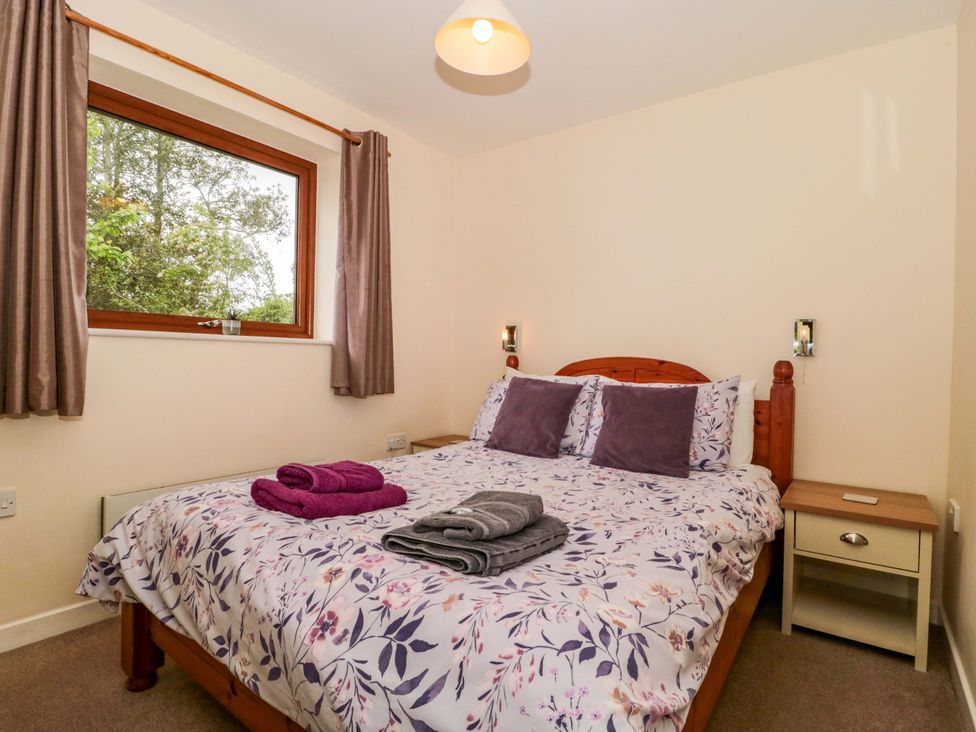 A bedroom with a bed and a nightstand at Orchard Cottage in Ledbury