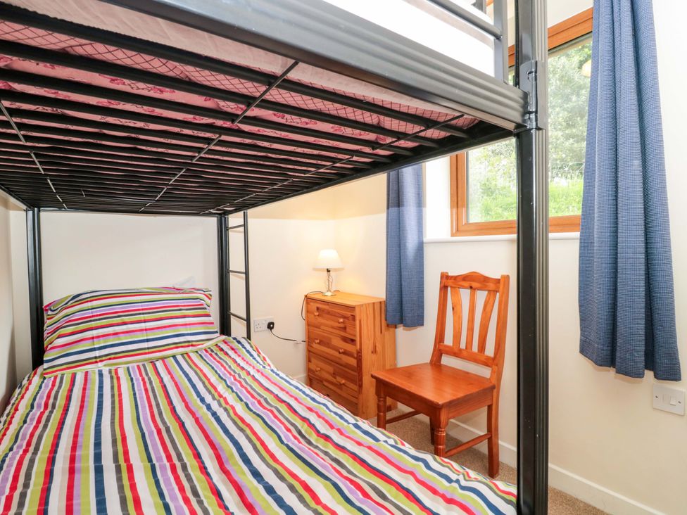 A bedroom with a bunk bed and wooden furniture at Orchard Cottage in Ledbury