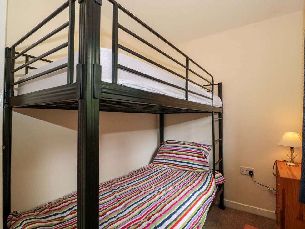 A bedroom with a bunk bed and nightstand at Orchard Cottage in Ledbury