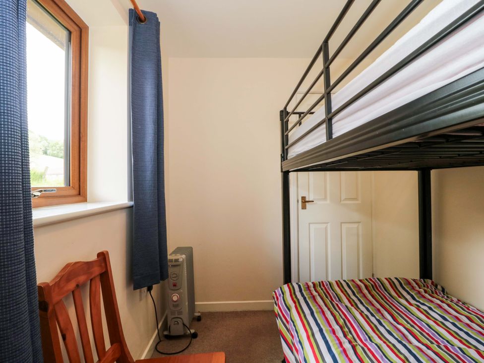 A bedroom with a bunk bed and chair at Orchard Cottage in Ledbury