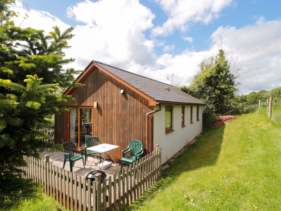 A cottage with a deck and chairs at Orchard Cottage in Ledbury