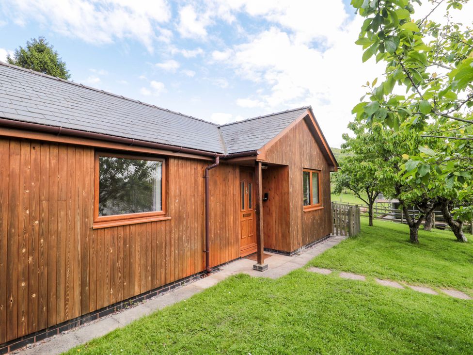 A wooden house with a pathway and lawn at Orchard Cottage in Ledbury