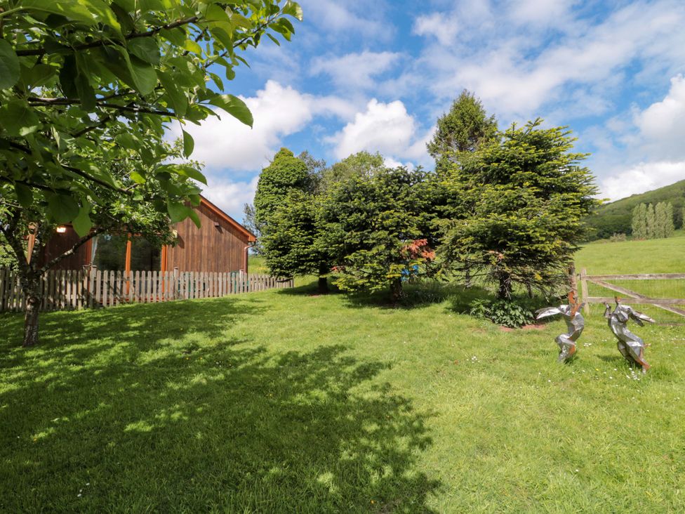 A garden with trees and a wooden building at Orchard Cottage in Ledbury