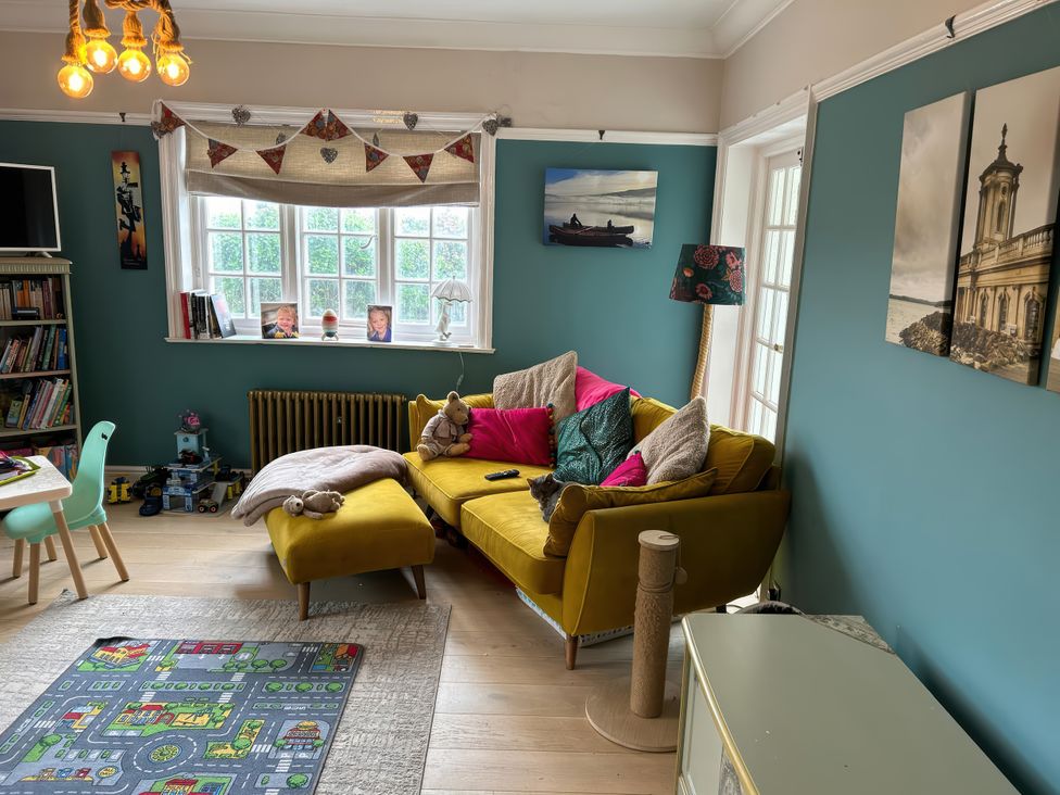 A living room with a yellow sofa and decorative items at Somerby in St. Bees