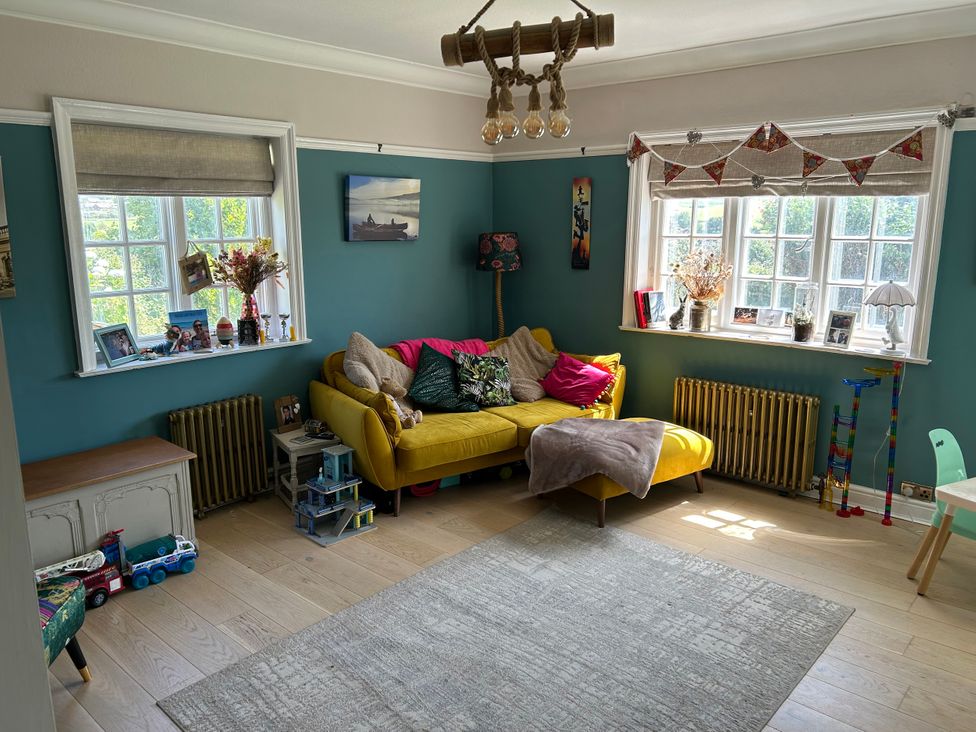 A living room with a yellow sofa and decorative items at Somerby in St. Bees
