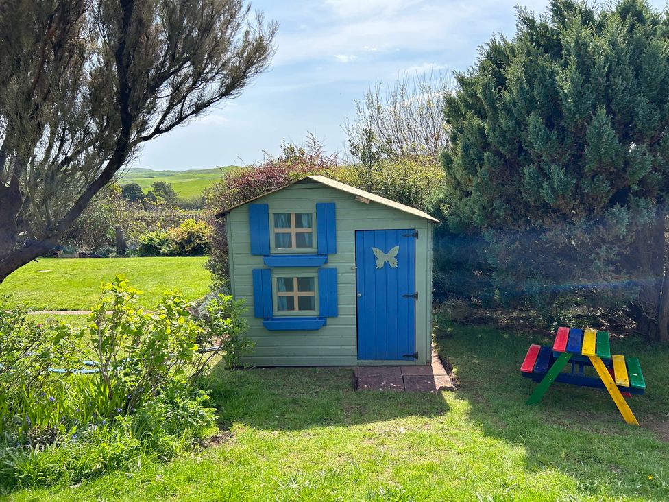A garden with a playhouse and picnic table at Somerby in St. Bees